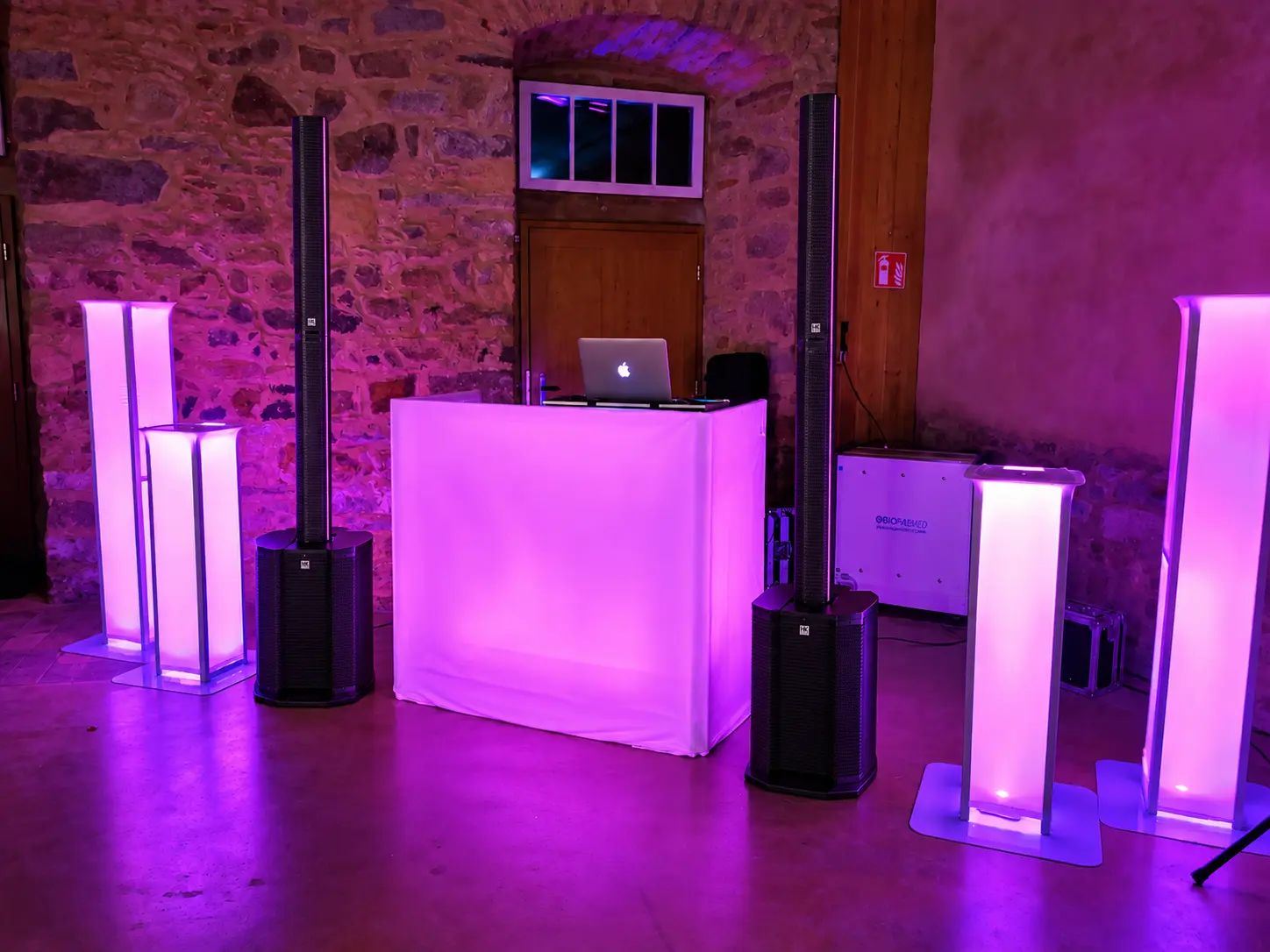 Weißes DJ-Pult mit Lautsprechern und magentafarbenen Lichtsäulen von DJ Events Hannover
