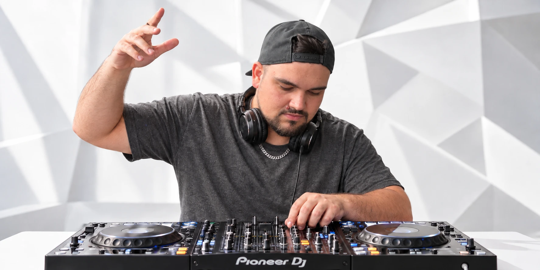 Tony Ray mit schwarzer Cap und Kopfhörern an seinem DJ-Pult
