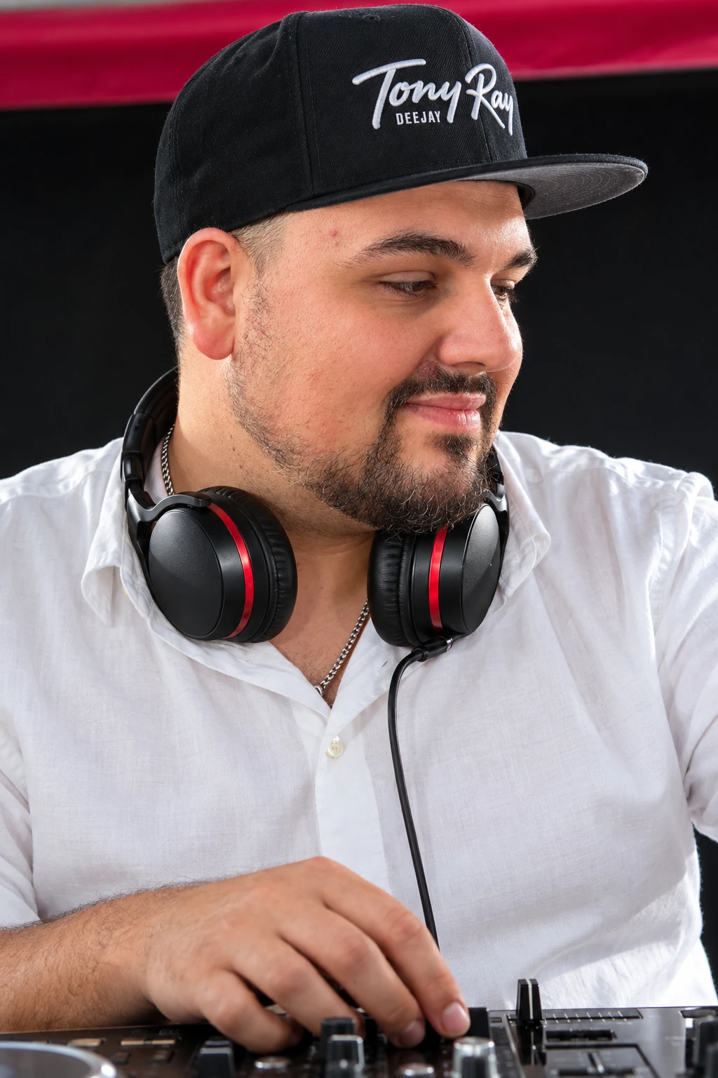 Tony Ray im weißen Hemd, mit seiner Logo-Cap und Kopfhörern am DJ-Pult